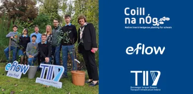The image shows a group of people including some school students and teachers standing in a green outdoor space. Two sign boards are held by the group which are logos of eFlow anf TII,. 